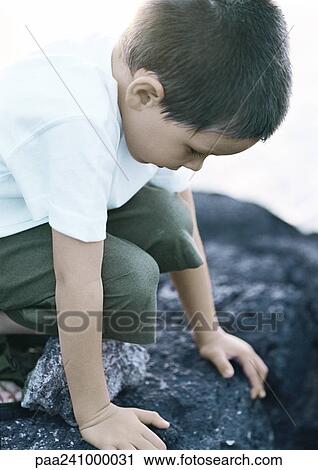 Child crouching on rock, close-up View Large Photo Image Stock Image - Child crouching on rock, close-up. Fotosearch
