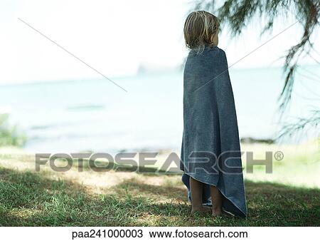 Stock Image - Child wrapped in towel, outside, rear view. Fotosearch