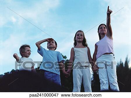 Children holding hands outdoors, one pointing, one shielding eyes, front view View Large Photo Image Stock Photo - Children holding hands outdoors, one pointing, one shielding eyes, front view. Fotosearch