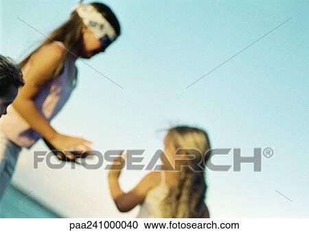 Stock Image - Children playing blind man's buff, blurred. Fotosearch