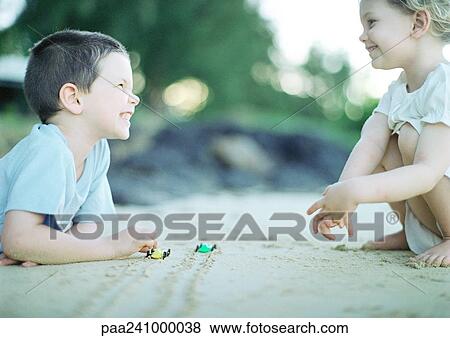 Stock Photo - Children playing on sand, side view. Fotosearch