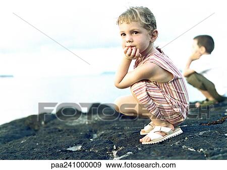 Stock Photo - Two children crouching on rock. Fotosearch