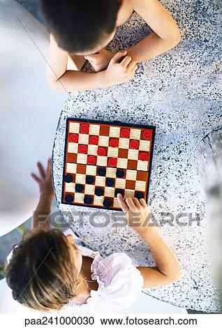 Stock Image - Two children playing checkers, view from directly above. Fotosearch