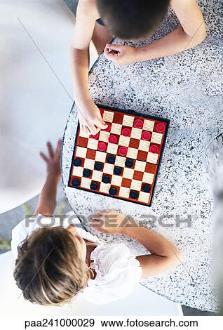 Stock Photo - Two children playing checkers, view from directly above. Fotosearch