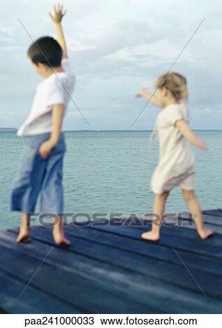 Two children standing on dock waving arms, blurred View Large Photo Image Stock Image - Two children standing on dock waving arms, blurred. Fotosearch