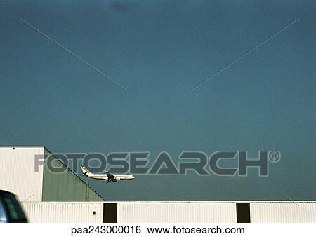 Airplane flying over building View Large Photo Image Stock Photograph - Airplane flying over building. Fotosearch