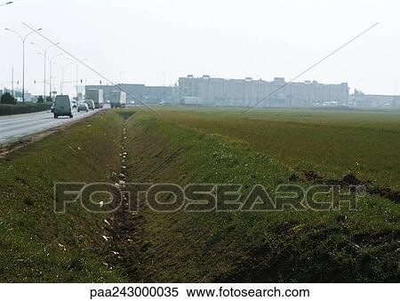 Stock Photography - Ditch along road, town in background. Fotosearch