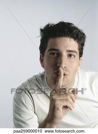 Young man looking at camera with finger in front of lips View Large Photo Image Stock Image - Young man looking at camera with finger in front of lips. Fotosearch