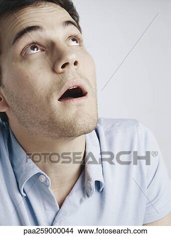 Young Man Looking Up With Mouth And Eyes Open Raising Eyebrows