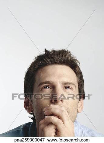 Young man with hands clasped in front of mouth, looking up View Large Photo Image Stock Photo - Young man with hands clasped in front of mouth, looking up. Fotosearch