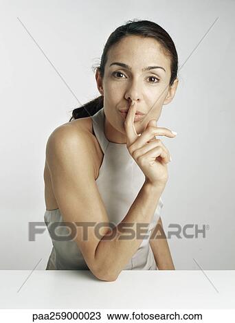 Young woman leaning on elbow with finger in front of lips View Large Photo Image Stock Image - Young woman leaning on elbow with finger in front of lips. Fotosearch