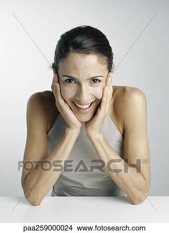 Young woman leaning on elbows, holding face between hands View Large Photo Image Picture - Young woman leaning on elbows, holding face between hands. Fotosearch