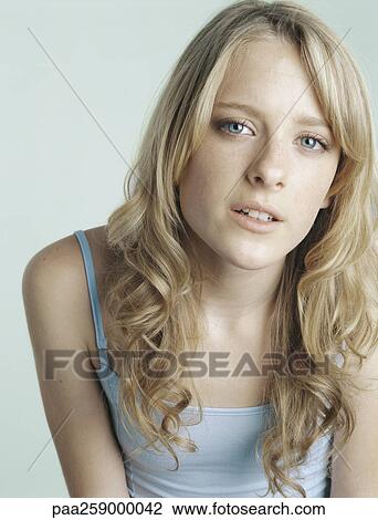 Stock Image - Young woman looking at camera with mouth slightly open, portrait. Fotosearch