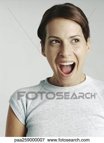 Stock Photo - Young woman looking out of frame with mouth wide open. Fotosearch