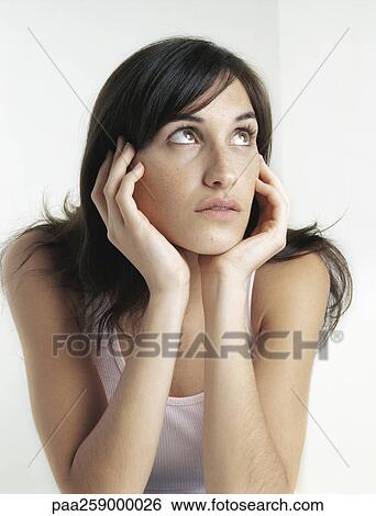 Young woman looking up and away, holding face between hands View Large Photo Image Stock Photograph - Young woman looking up and away, holding face between hands. Fotosearch