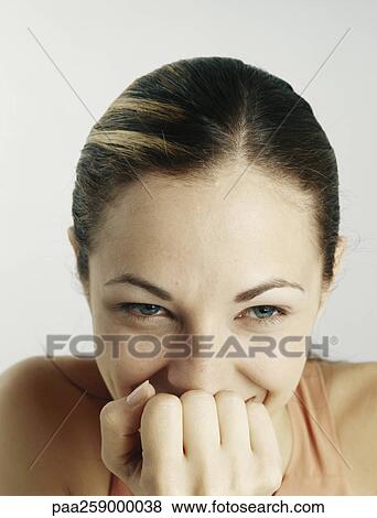 Young woman smiling with fist in front of mouth, close-up View Large Photo Image Stock Photo - Young woman smiling with fist in front of mouth, close-up. Fotosearch