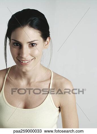 Young woman wearing tank top smiling at camera View Large Photo Image Stock Image - Young woman wearing tank top smiling at camera. Fotosearch