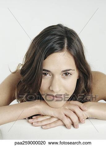 Young woman with bare shoulders resting head on clasped hands, smiling View Large Photo Image Stock Image - Young woman with bare shoulders resting head on clasped hands, smiling. Fotosearch
