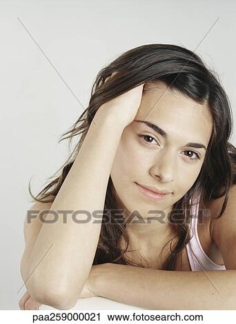 Young woman with hand in hair looking at camera, tilting head View Large Photo Image Stock Image - Young woman with hand in hair looking at camera, tilting head. Fotosearch