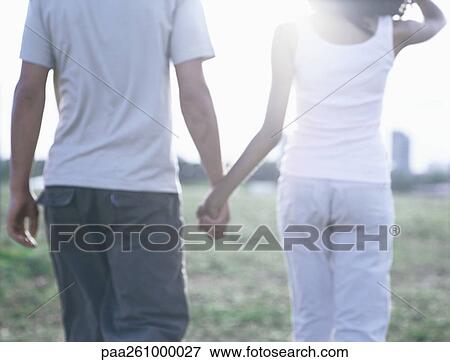 Young couple walking hand in hand, mid-section View Large Photo Image Stock Photo - Young couple walking hand in hand, mid-section. Fotosearch