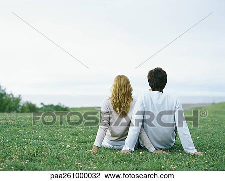 Young man and young woman sitting side by side on grass, propped up with hands, rear view View Large Photo Image Stock Image - Young man and young woman sitting side by side on grass, propped up with hands, rear view. Fotosearch
