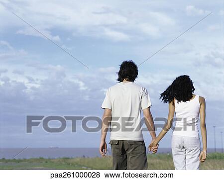Young man and young woman walking hand in hand View Large Photo Image Stock Photo - Young man and young woman walking hand in hand. Fotosearch