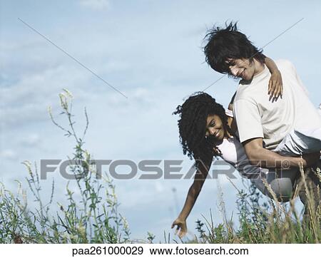 Stock Photo - Young man carrying young woman piggyback. Fotosearch