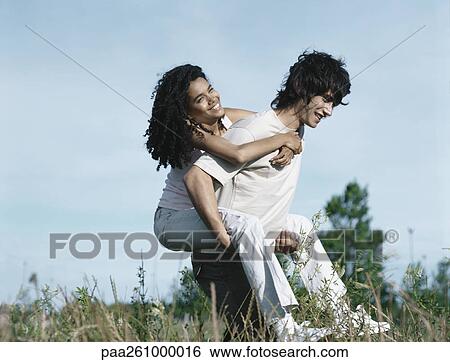 Young man carrying young woman piggyback through tall grass View Large Photo Image Stock Photograph - Young man carrying young woman piggyback through tall grass. Fotosearch