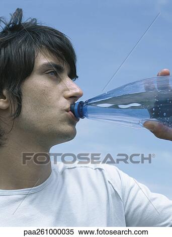 Young man drinking from bottle, looking out of frame, close-up View Large Photo Image Stock Photography - Young man drinking from bottle, looking out of frame, close-up. Fotosearch
