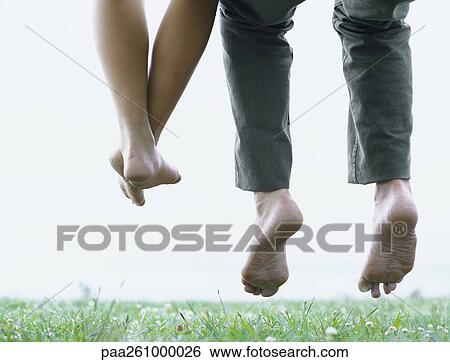 Stock Photograph - Young man's and youngs woman's lower legs, off the ground. Fotosearch
