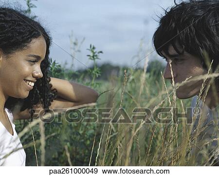 Stock Photo - Young woman and young man face to face in tall grass. Fotosearch