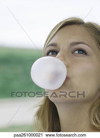 Young woman blowing bubble with chewing gum, looking up, close-up View Large Photo Image Stock Image - Young woman blowing bubble with chewing gum, looking up, close-up. Fotosearch
