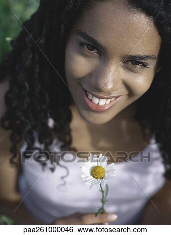 Young woman holding up daisy, portrait View Large Photo Image Stock Photograph - Young woman holding up daisy, portrait. Fotosearch