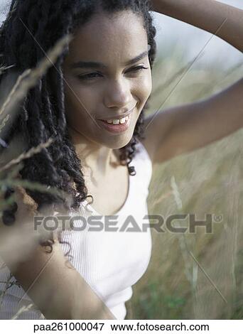 Young woman sitting in tall grass with hand behind head View Large Photo Image Stock Photo - Young woman sitting in tall grass with hand behind head. Fotosearch