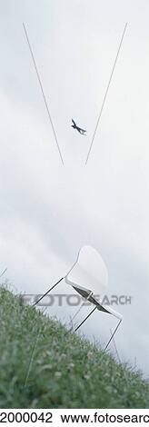 Stock Image - Chair on grass with plane in sky in background. Fotosearch