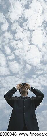 Man looking through binoculars, sky in background, low angle view View Large Photo Image Stock Photo - Man looking through binoculars, sky in background, low angle view. Fotosearch