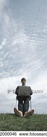 Man sitting barefoot in chair with laptop on lap, sky in background, low angle view View Large Photo Image Stock Photograph - Man sitting barefoot in chair with laptop on lap, sky in background, low angle view. Fotosearch