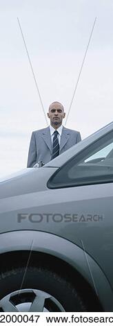 Stock Photo - Man standing behind car. Fotosearch