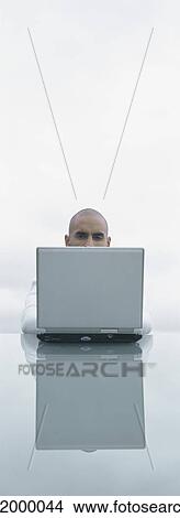 Picture - Top of man's head seen over back of laptop screen, outdoors. Fotosearch