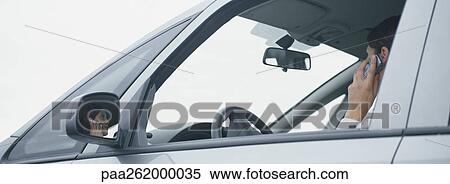 Stock Photography - Woman in car talking on cell phone, reflection in rear view mirror. Fotosearch