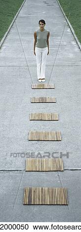 Woman standing in front of path of wooden rectangles View Large Photo Image Stock Image - Woman standing in front of path of wooden rectangles. Fotosearch
