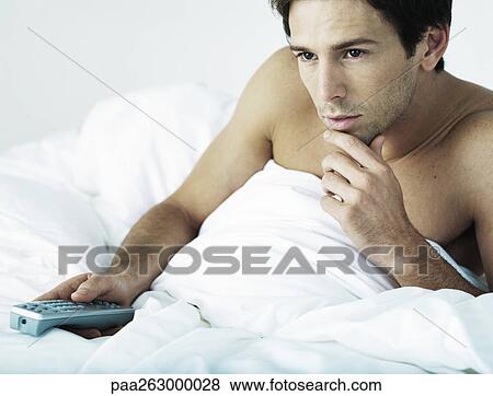 Man in bed under covers, sitting up, pointing remote control, touching chin View Large Photo Image Stock Photo - Man in bed under covers, sitting up, pointing remote control, touching chin. Fotosearch