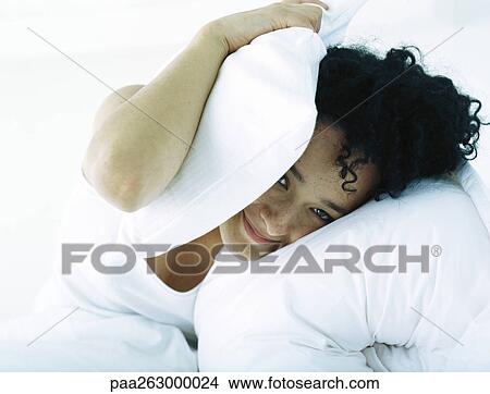 Picture - Woman in bed covering head with pillow. Fotosearch