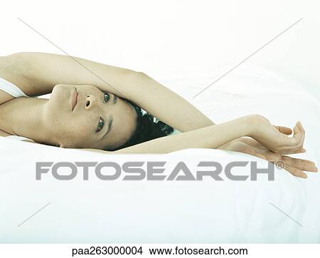 Woman lying on bed with arms crossed at wrists above head View Large Photo Image Picture - Woman lying on bed with arms crossed at wrists above head. Fotosearch