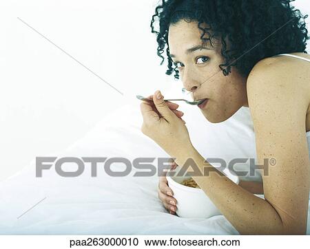 Woman lying on stomach on bed eating from a bowl View Large Photo Image Stock Image - Woman lying on stomach on bed eating from a bowl. Fotosearch