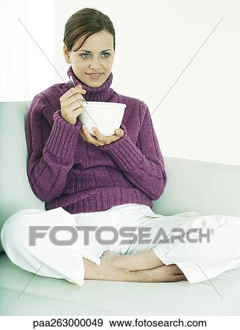 Woman sitting indian style on sofa holding bowl and utensil View Large Photo Image Stock Photo - Woman sitting indian style on sofa holding bowl and utensil. Fotosearch