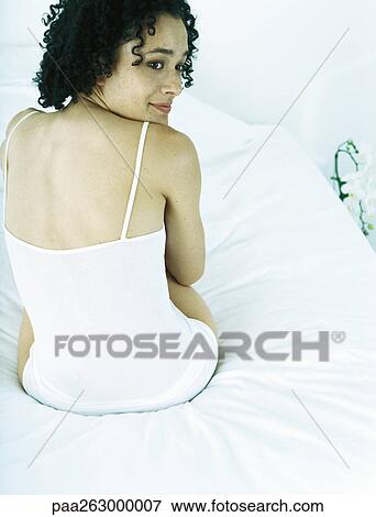 Woman sitting on bed wearing underclothes, looking over shoulder, rear view View Large Photo Image Stock Photo - Woman sitting on bed wearing underclothes, looking over shoulder, rear view. Fotosearch