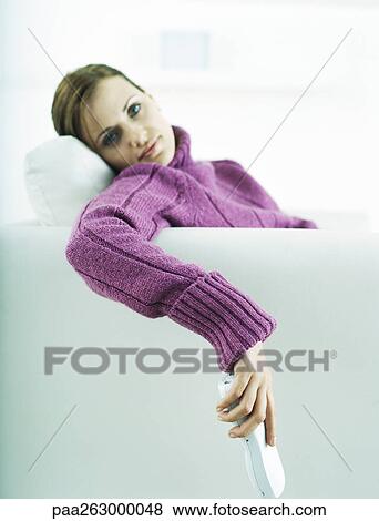 Woman sitting on sofa, holding cell phone View Large Photo Image Stock Photo - Woman sitting on sofa, holding cell phone. Fotosearch