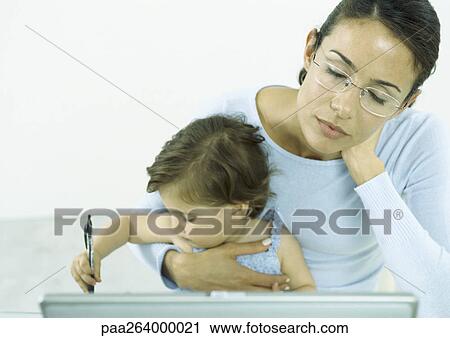 Stock Image - Woman with eyes closed holding little girl drawing with pen. Fotosearch