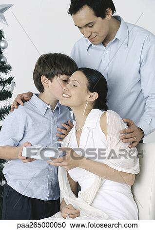 Boy giving gift to mother, father standing behind them View Large Photo Image Stock Image - Boy giving gift to mother, father standing behind them. Fotosearch